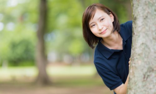 木の陰から見つめる女性