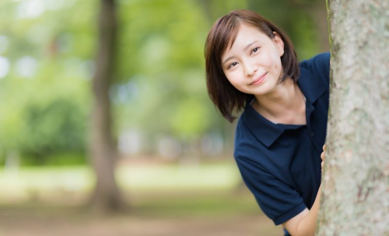 木の陰から見つめる女性
